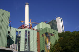Bild vergrößern: Grünes Gebäude mit weißem Industrieschornstein.