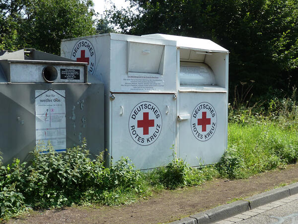 Bild vergrößern: Zwei weie Altkleidercontainer des deutschen roten Kreuzes stehen neben einem Glascontainer.