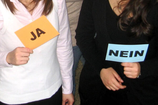 Bild vergrößern: Zwei weibliche Personen halten jeweils ein kleines Schild, eines mit der Aufschrift "JA" das andere mit "NEIN".