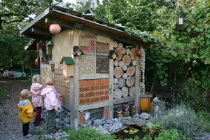 Bild vergrößern: Zwei kleine Mädchen stehen an einem Wildbienenhaus.