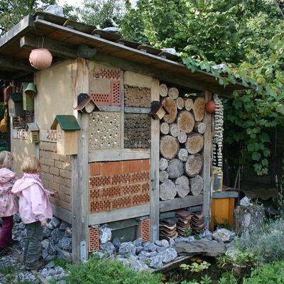 Bild vergrößern: Zwei kleine Mdchen stehen an einem Wildbienenhaus.