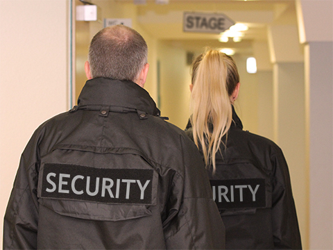 Bild vergrößern: Ein Mann und eine Frau mit schwarzen Jacken mit der Aufschrift: "Security".