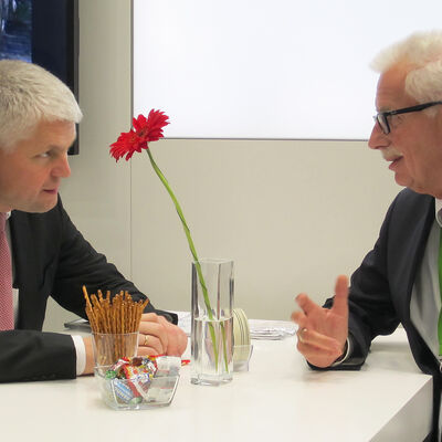 Bild vergrößern: Landrat Thomas Hendele sitzt an einem Tisch seinem Gesprächspartner Staatssekretär Christoph Dammermann gegenüber.