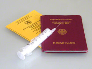 Bild vergrößern: Ein Impfbuch, ein Reisepass und eine Spritze liegen übereinander.
