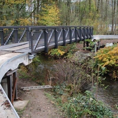 Bild vergrößern: Brcke ber einem Bach in einem Waldgebiet.