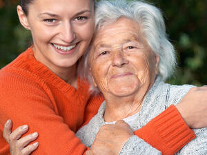 Bild vergrößern: Eine junge Frau hält eine ältere Dame im Arm.