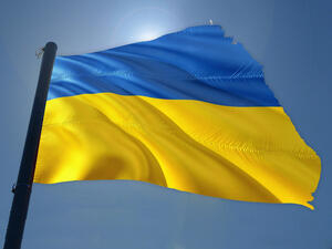 Bild vergrößern: Ukrainische Flagge ist vor einem blauen Himmel gehisst.