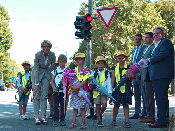 NRW-Schulministerin Dorothee Feller begleitet Schulanfänger der Grundschule Anne Frank in Ratingen auf ihrem Schulweg entlang einer Straße.